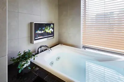 a bath tub in a bathroom with a tv on the wall at Hotel Niwa Tokyo in Tokyo