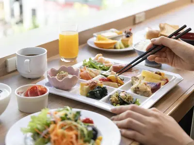 a table with plates of food and a person holding chopsticks at Hotel Gracery Ginza in Tokyo