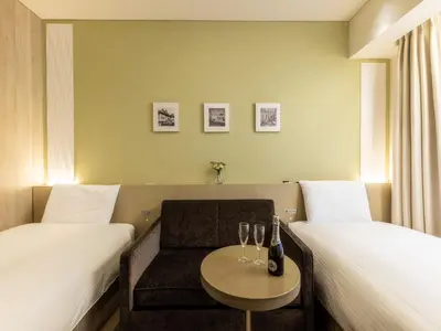 a hotel room with two beds and a table with wine glasses at Hotel Gracery Ginza in Tokyo