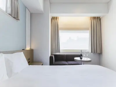 a hotel room with a bed and a chair and a window at Hotel Gracery Ginza in Tokyo