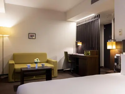 a hotel room with a bed and a chair and a table at Hotel Gracery Tokyo Tamachi in Tokyo