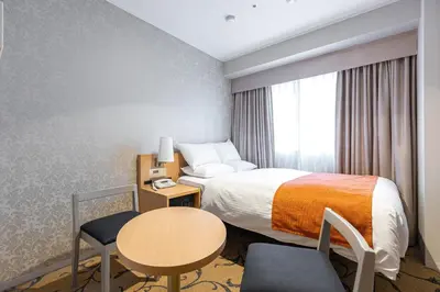 a hotel room with a bed and a table and chair at Hotel Rose Garden Shinjuku in Tokyo
