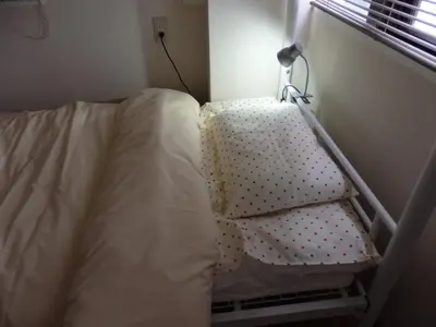 an unmade bed in a small room with a pillow at Backpacker's Mini House in Tokyo