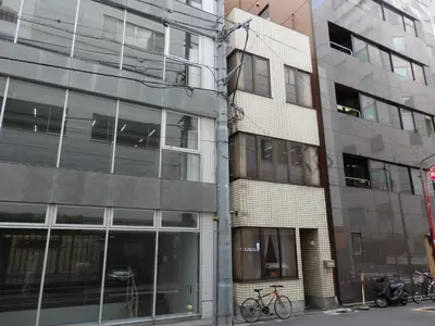 a building with a bike parked in front of it at Backpacker's Mini House in Tokyo