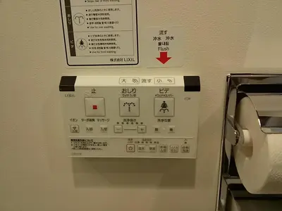 a sign on a wall next to a toilet paper dispenser at the b shimbashi in Tokyo