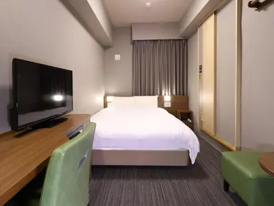 a hotel room with a bed and a flat screen tv at Dormy Inn Tokyo Hatchobori - Natural Hot Spring in Tokyo