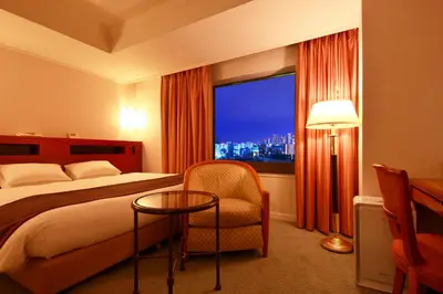 a hotel room with a bed and a chair and a window at Hotel East 21 Tokyo in Tokyo
