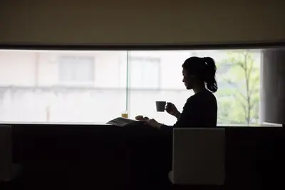 a woman sitting in front of a window holding a cup at the b suidobashi in Tokyo
