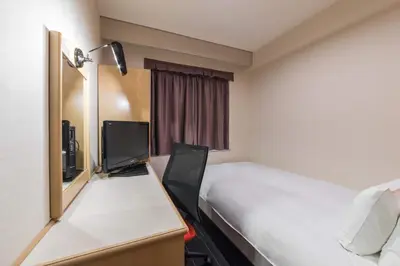 a hotel room with a bed and a desk with a computer at the b suidobashi in Tokyo
