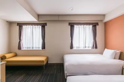 a hotel room with two beds and a couch at the b suidobashi in Tokyo