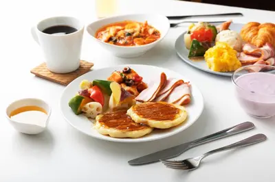 a white table with plates of breakfast foods and a cup of coffee at the b suidobashi in Tokyo