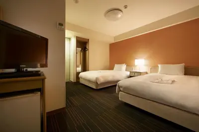 a hotel room with two beds and a flat screen tv at the b suidobashi in Tokyo