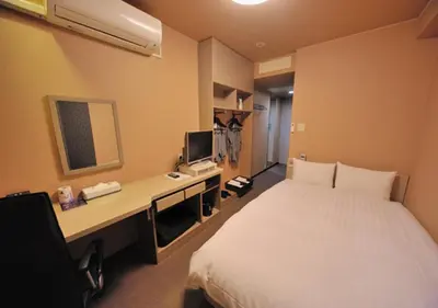a hotel room with a bed and a desk with a computer at Dormy Inn EXPRESS Asakusa in Tokyo
