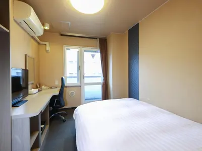 a hotel room with a bed and a desk and a television at Dormy Inn EXPRESS Asakusa in Tokyo