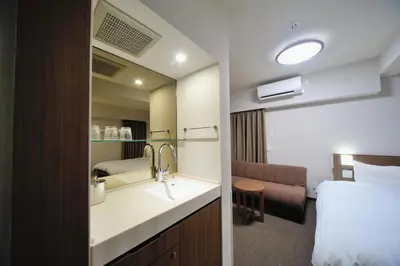 a hotel room with a sink and a bed at Dormy Inn Express Meguro Aobadai Hot Spring in Tokyo