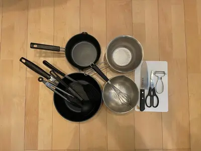 a group of frying pans and utensils on a wooden floor at COTO Tokyo Shibuya 2 in Tokyo