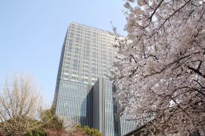 a tall glass building withakuraakura trees in front of it at The Capitol Hotel Tokyu in Tokyo