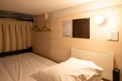 a room with a bed and a window and avertisement at Hotel Owl Tokyo Nippori in Tokyo