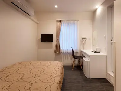 a bedroom with a bed and a desk and a window at Hotel New Tohoku in Tokyo