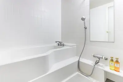 a white bathroom with a shower and a sink at HOTEL MYSTAYS Kameido in Tokyo