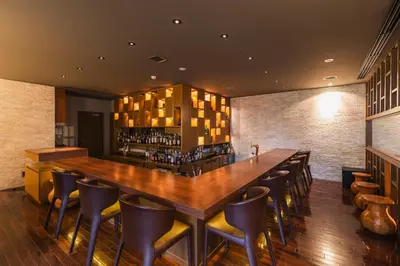 a bar in a restaurant with a long wooden table and chairs at Hotel Sunroute Plaza Shinjuku in Tokyo
