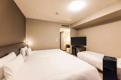 a hotel room with two beds and a flat screen tv at Hotel Sunroute Plaza Shinjuku in Tokyo