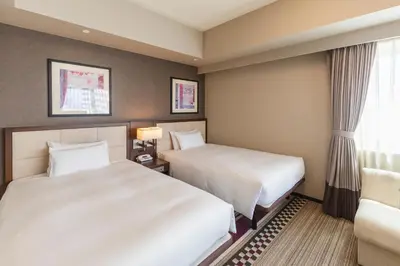 a hotel room with two beds and a window at Hotel Sunroute Plaza Shinjuku in Tokyo