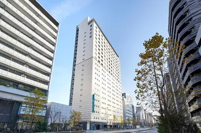 a tall white building in the middle of a city at Sotetsu Fresa Inn Higashi Shinjuku in Tokyo