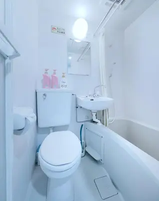a white bathroom with a toilet and a sink at Tokyo Sakura hotel in Tokyo
