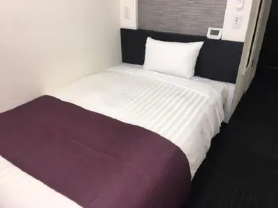 a bedroom with a large white bed with a purple blanket at Ueno Urban Hotel in Tokyo