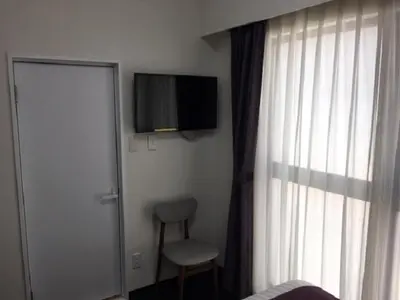 a bedroom with a tv and a chair and a window at Ueno Urban Hotel in Tokyo