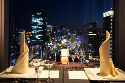 a table with wine glasses and a view of the city at Hotel Metropolitan Tokyo Marunouchi in Tokyo
