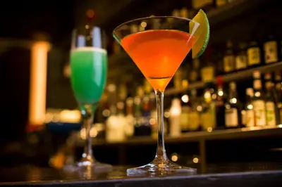 two martini glasses sitting on a bar with a lime at Hotel Metropolitan Tokyo Marunouchi in Tokyo