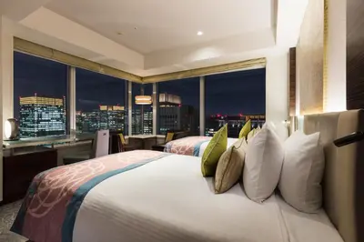 a bedroom with a large bed with a city view at Hotel Metropolitan Tokyo Marunouchi in Tokyo