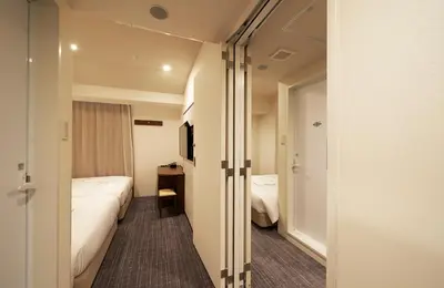 a small hotel room with a bed and a window at Sotetsu Fresa Inn Tokyo Roppongi in Tokyo