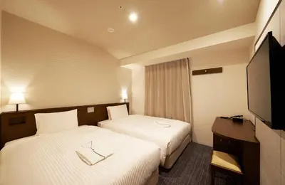 a hotel room with two beds and a flat screen tv at Sotetsu Fresa Inn Tokyo Roppongi in Tokyo