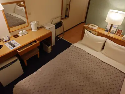 a hotel room with a bed and a desk and a mirror at Smile Hotel Tokyo Shinkoiwa in Tokyo