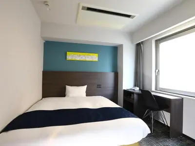a bedroom with a bed and a desk and a window at KOKO HOTEL Ikebukuro East - formerly Hotel Wing International Ikebukuro in Tokyo