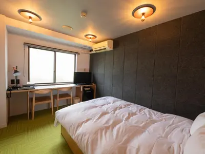 a bedroom with a bed and a desk and a window at Sakura Ryokan Asakusa Iriya in Tokyo