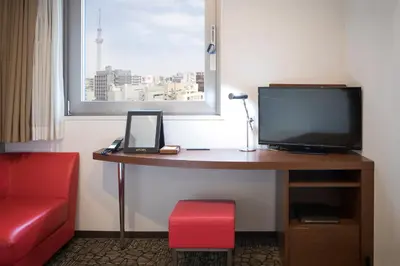 a room with a desk with a television and a red chair at HOTEL MYSTAYS Asakusabashi in Tokyo