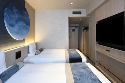 two beds in a hotel room with a flat screen tv at HOTEL MYSTAYS Ochanomizu Conference Center in Tokyo