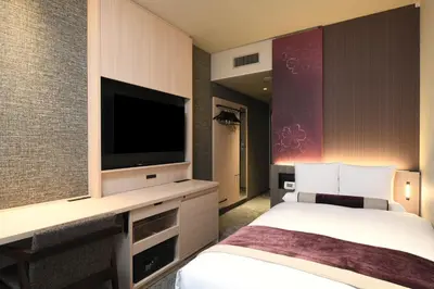 a hotel room with a bed and a flat screen tv at HOTEL MYSTAYS Ochanomizu Conference Center in Tokyo