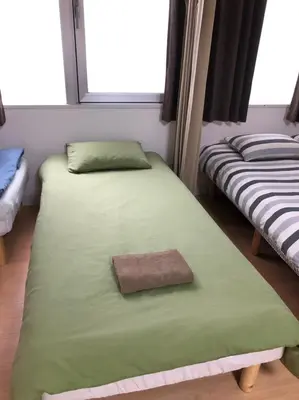 two twin beds in a room with two windows at Issyuku hostel in Tokyo