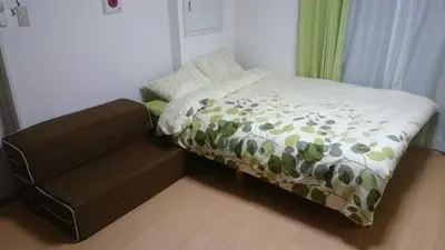a small bed in a room with a chair at Issyuku hostel in Tokyo