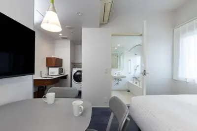 a white bedroom with a table and chairs and a bathroom at Tokyu Stay Ikebukuro in Tokyo