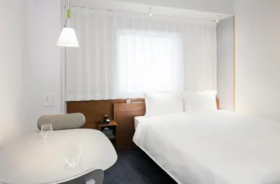 a bedroom with two beds and a table and a chair at Tokyu Stay Ikebukuro in Tokyo