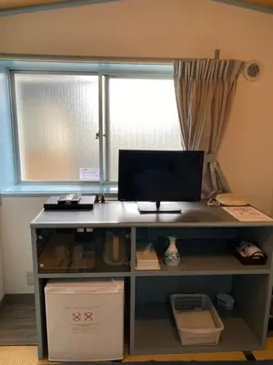 a desk with a computer on it in front of a window at Oyado Cocochi in Tokyo