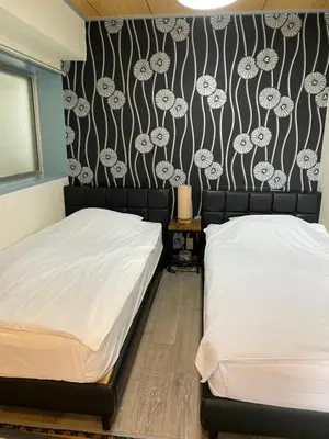 a bedroom with two beds and a wall with floral wallpaper at Oyado Cocochi in Tokyo