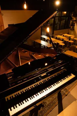 a piano sitting inside of a room with tables at Tokyo Guest House Ouji Music Lounge in Tokyo