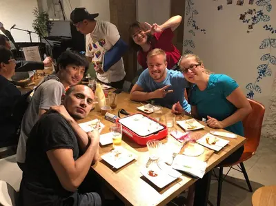 a group of people sitting around a table eating at Tokyo Guest House Ouji Music Lounge in Tokyo